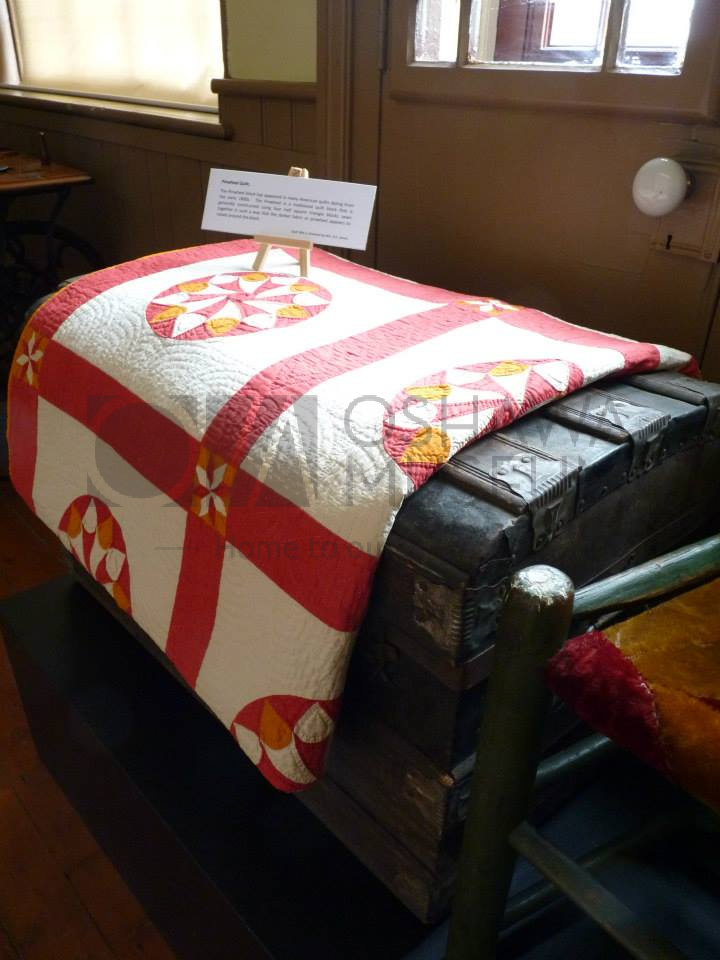 A colourful quilt resting on top of a wooden trunk